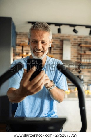 Mature man using smartphone while exercising at home