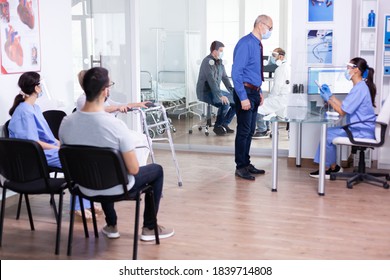 Mature Man Waiting In Hospital Lobby And Talking With Nurse At Reception Wearing Face Mask Against Coronavirus. Social Distancing, Medic, Covid-19, Man, Worried, Protection, Corona,