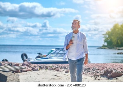 Mature Man Walking On Seashore In Good Mood