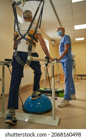 Mature Man Walking In Parallel Bars At Rehabilitation Room