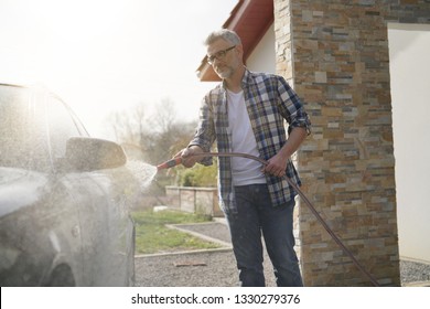 Mature Man Washing His Car In Driveway