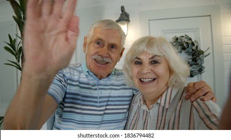 Mature Man, Woman Making Selfie. Senior Elderly Caucasian Couple Using Mobile Phone For Video Call In Porch At Home. Talking On Webcam, Waving Hand. Social Media Network On Phone