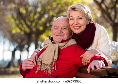 Mature Man And Woman Sitting Comfortably On Bench In Park