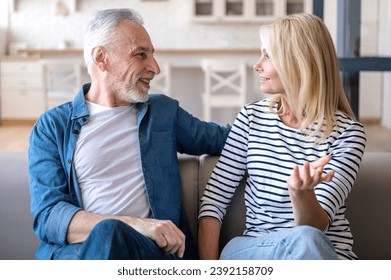 Mature man and woman talking and relaxing on couch in dining room. Couple involved in interesting pleasant conversation at home. Enjoy weekend or date - Powered by Shutterstock