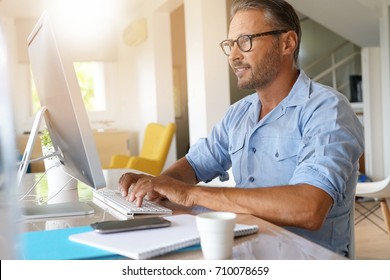 Mature Man Working From Home On Desktop Computer