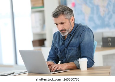 Mature Man Working On Laptop In School Office