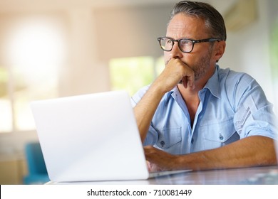 Mature man working on laptop computer at home