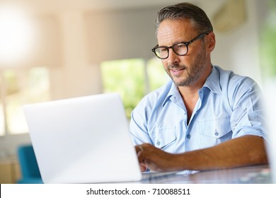 Mature Man Working On Laptop Computer At Home