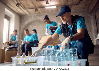 Mature man working as volunteer at community center and arranging donated food and water in boxes. - Powered by Shutterstock