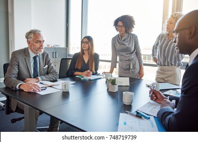 Mature Manager Talking To A Diverse Group Of Employees During A Meeting Around A Table In A Boardroom