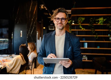 Mature manager using tablet computer during offline meeting in office - Shutterstock ID 2250135729