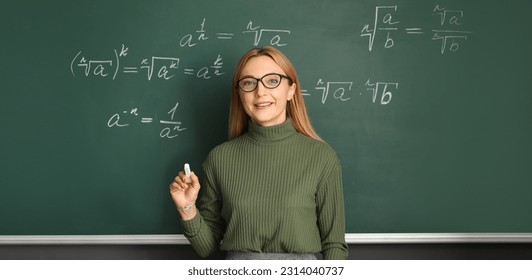 Mature maths teacher near blackboard in classroom - Powered by Shutterstock