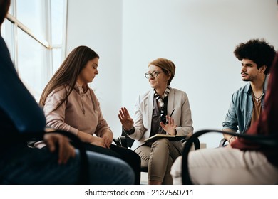 Mature Mental Health Professional Communicating With Group Of People During Counseling At Community Center. 