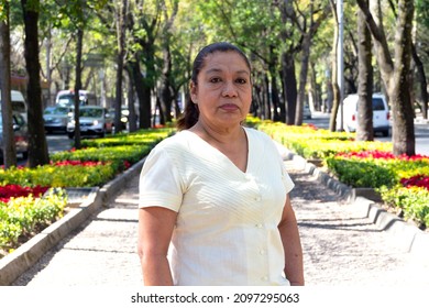 Mature Mexican Lady Looking In Front Of The Camera, Standing, Between City Streets. Latin Woman Looking At The Camera. Serious Attitude.