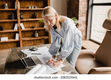 Mature middle-aged architect engineer drawing on architectural plans, engineer working on new building project construction at office desk. - Powered by Shutterstock