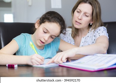 A Mature mother helping her child with homework at home.