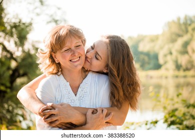 Mãe madura abraçando com sua filha adolescente ao ar livre na natureza em dia ensolarado