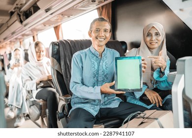 mature muslim couple using showing blank tablet screen to camera while riding a bus - Powered by Shutterstock