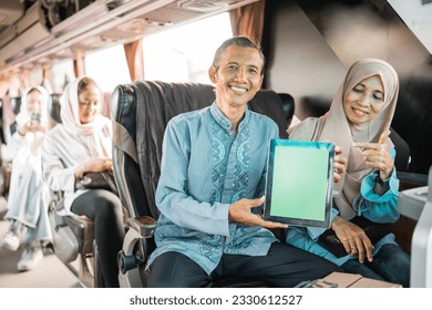 mature muslim couple using showing blank tablet screen to camera while riding a bus - Powered by Shutterstock