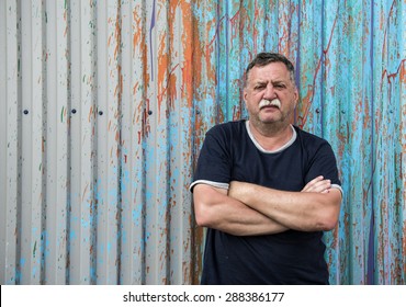 Mature Mustachioed Man Sitting Against The Wall. 