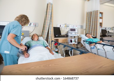 Mature Nurse Examining Patient In Post Anesthesia Care Unit