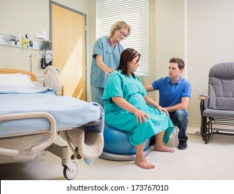 Mature nurse and man assisting pregnant woman on exercise ball in hospital - Powered by Shutterstock