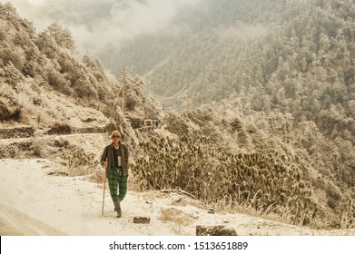 A Mature Old (a Man Of Nepalese Ethnicity) Solitary Hiker On A Hiking Trail Walking Alone In A Beautiful Winter Environment Of North East Himalayan Mountain Range. Nepal, South Asia.