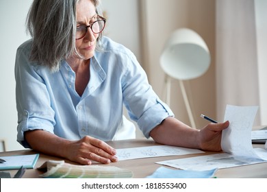 Mature old adult elegant woman fashion designer drawing creative sketches on table. Beautiful sophisticated middle aged grey-haired lady entrepreneur creating new fashion design cloth in atelier. - Powered by Shutterstock