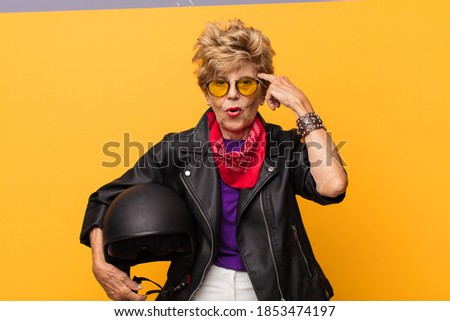 mature old beautiful woman feeling confused and puzzled, showing you are insane, crazy or out of your mind. motorbike concept