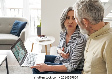 Mature Old Grandparents Couple Patients Having Video Chat With Virtual Doctor Using Laptop Computer Sit On Couch At Home. Online Telemedicine Meeting. Senior Health, Telehealth Healthcare Consultation