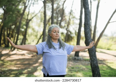 Mature old woman with dreadlocks practicing yoga and tai chi outdoors - wellbeing and wellness - Powered by Shutterstock