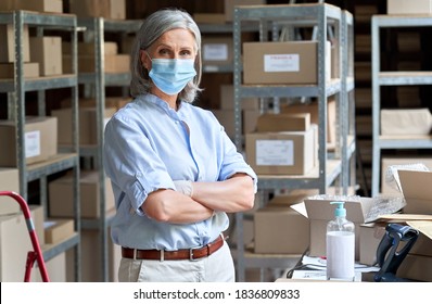 Mature Older Business Woman Retail Seller, Entrepreneur, Small Business Owner Wearing Face Mask And Gloves For Covid 19 Protection Looking At Camera Standing In Delivery Storage Warehouse, Portrait.