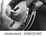 mature, older man, male playing five string banjo outside in monochrome black and white close-up of hand and fingers bluegrass music	