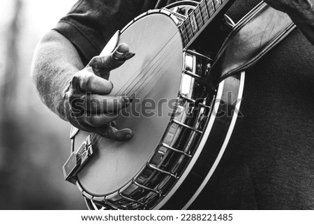 mature, older man, male playing five string banjo outside in monochrome black and white close-up of hand and fingers bluegrass music	