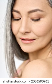 Mature Older Mid Aged Asian Woman Of 50s With Grey Hair Looking At Her Perfect Skin. Advertising Of Spa Procedures For Women In Menopause. Skincare, Cosmetology, Dermatology Ads. Close Up Portrait.