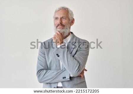Mature older successful business man investor, thoughtful middle aged senior professional businessman holding hand on chin looking away thinking making decision standing isolated on white wall.