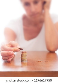 Mature Older Woman Putting Coins Into A Pile, Heap, On Table. Defocussed High Key Background. Poverty Concept, Counting Pennies, Small Change. Euros.