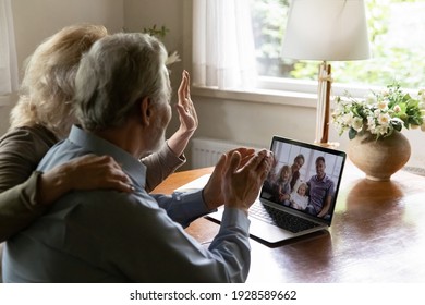 Mature pensioner grandparents couple talks to children and grandchildren, elder OAP use laptop for video call, wave hello. Screen view of happy young 60s parents and two kids during covid 19 concept - Powered by Shutterstock