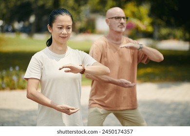 Mature people doing arm circle exercise when working out outdoors - Powered by Shutterstock