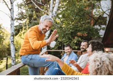 Mature people enjoying in a home garden, smiling and relaxing. Friends talking jokes and give five for good mood. Copy space - Powered by Shutterstock