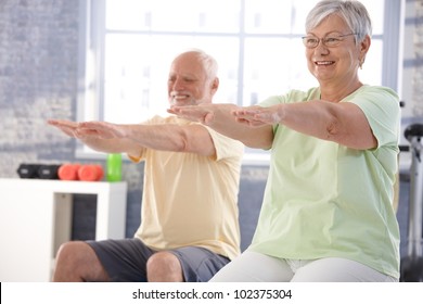 Mature People Exercising Happily In The Gym.