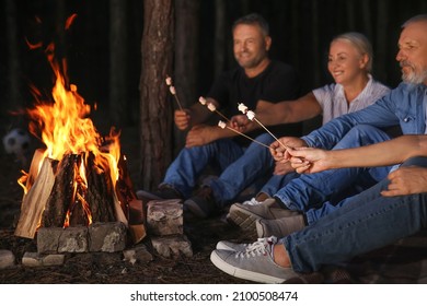 Mature People Roasting Marshmallows Near Fire On Summer Evening