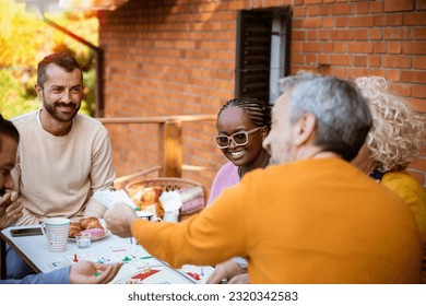 Mature people socialize playing cards with laughter and stories on the house porch outside - Powered by Shutterstock