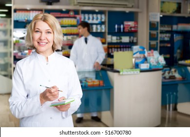 Mature Pharmacist And Pharmacy Technician Posing In Pharmacy