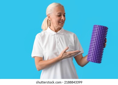 Mature Physiotherapist With Foam Roller On Blue Background