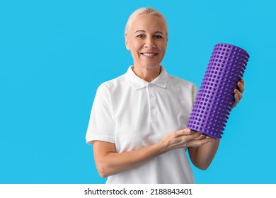 Mature Physiotherapist With Foam Roller On Blue Background