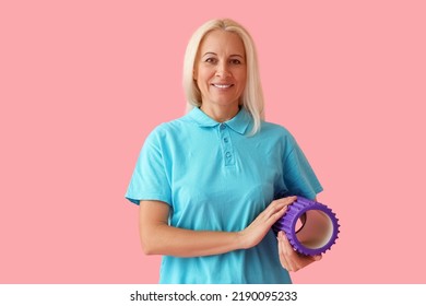 Mature Physiotherapist With Foam Roller On Pink Background