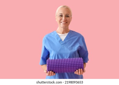 Mature Physiotherapist With Foam Roller On Pink Background