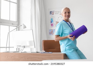 Mature Physiotherapist With Foam Roller In Rehabilitation Center