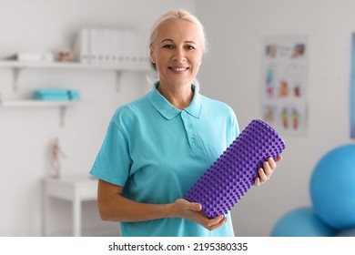 Mature Physiotherapist With Foam Roller In Rehabilitation Center